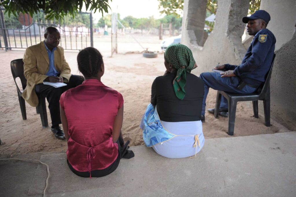 A reporter talks to the 16-year-old girl who was allegedly gang-raped by six boys, aged between 15 and 17 years, They had apparently been drinking at a local tavern despite being underage. With her is her mother and a policeman