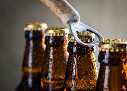 Brown ice cold beer bottles with water drops and old opener